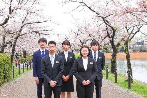 桜並木での新入社員の集合写真